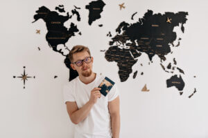 A boy in white shirt standing in front of world map on the wall.