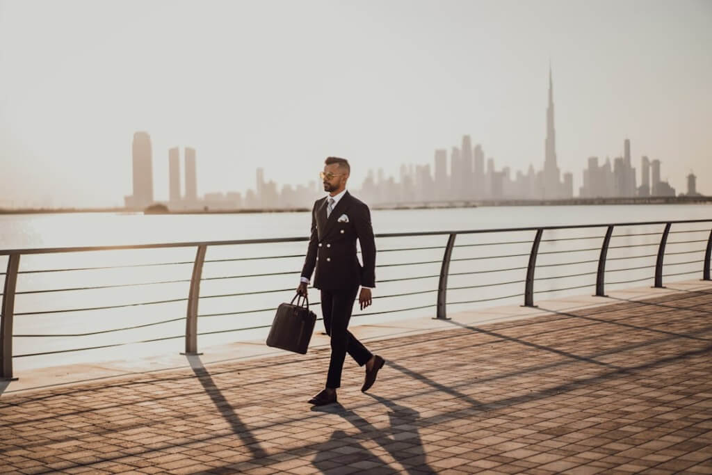 A well-suited man walking on corniche side.
