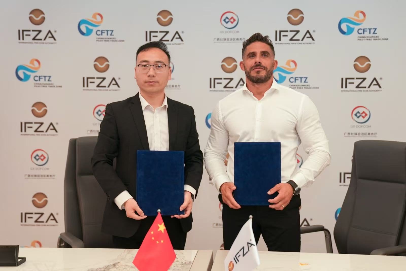 Chris Elliott and partner holding signed IFZA documents